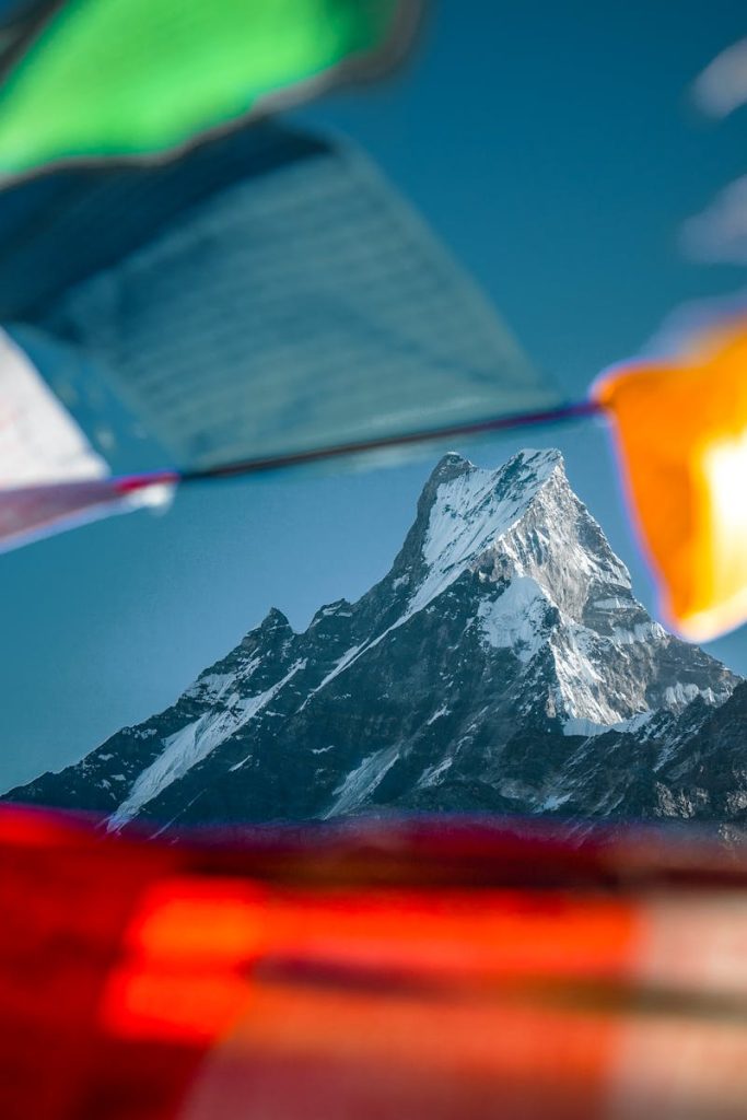 Majestic mountain peak surrounded by vibrant prayer flags in the Himalayas, Nepal.
