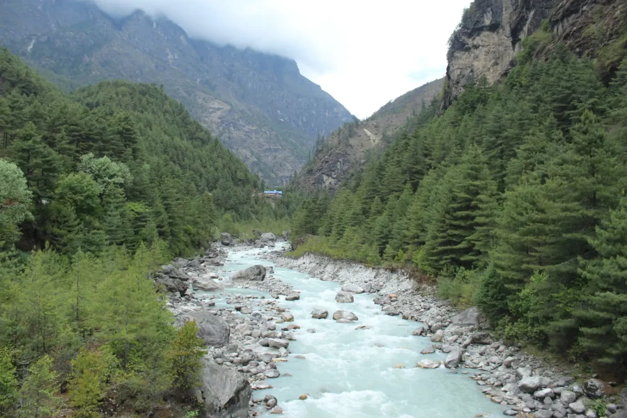 a view of green blue clean river in the middle of hills