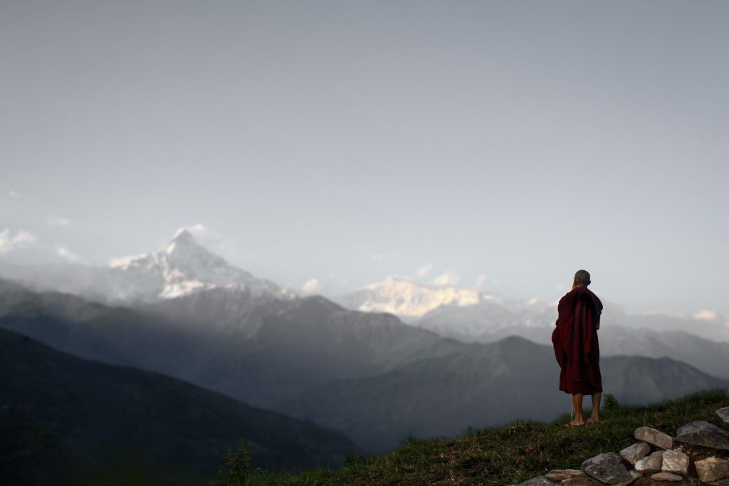 a monk sthaning in front of the mountain range