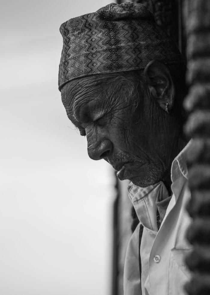 Black and white portrait of an elderly man wearing traditional Nepali attire in Kirtipur.