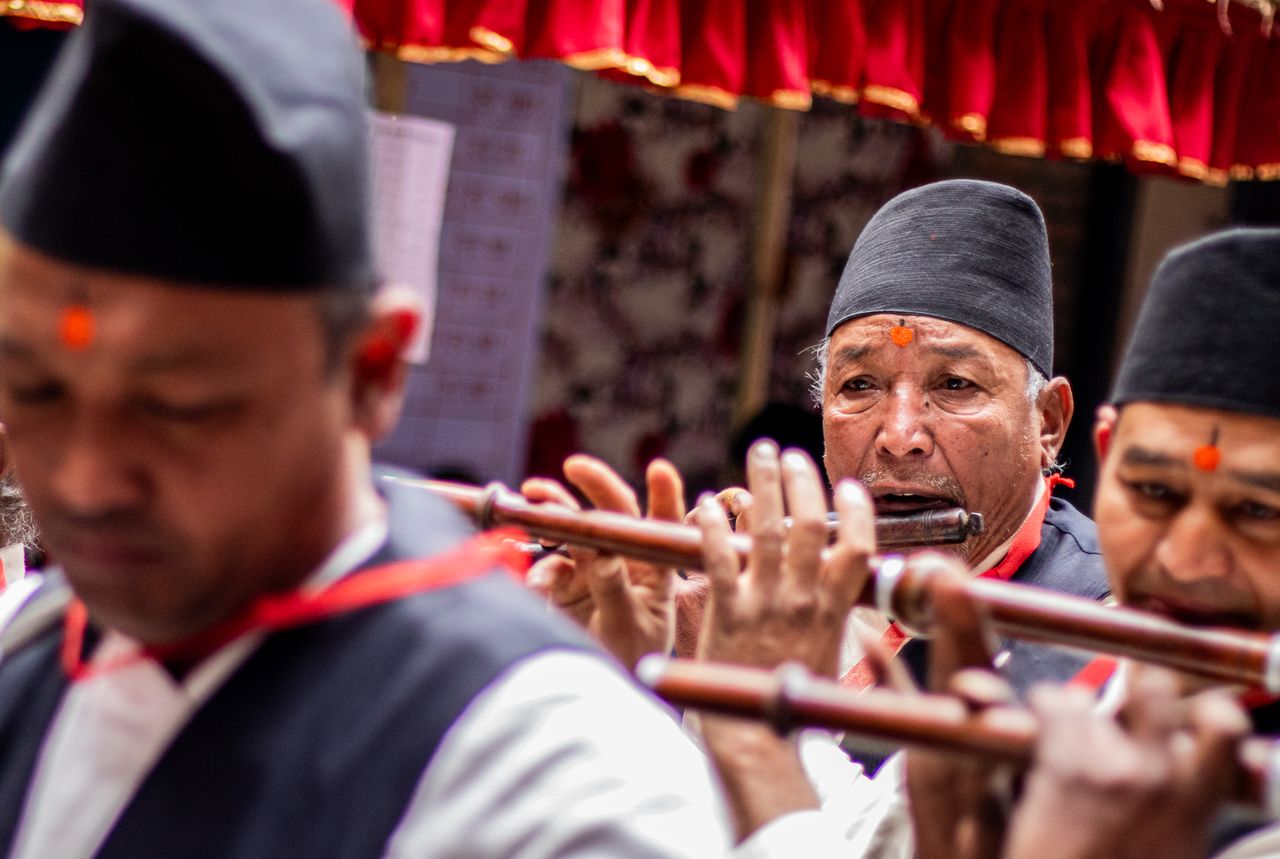 A group of traditional musicians playing flutes during a cultural event, wearing traditional attire.