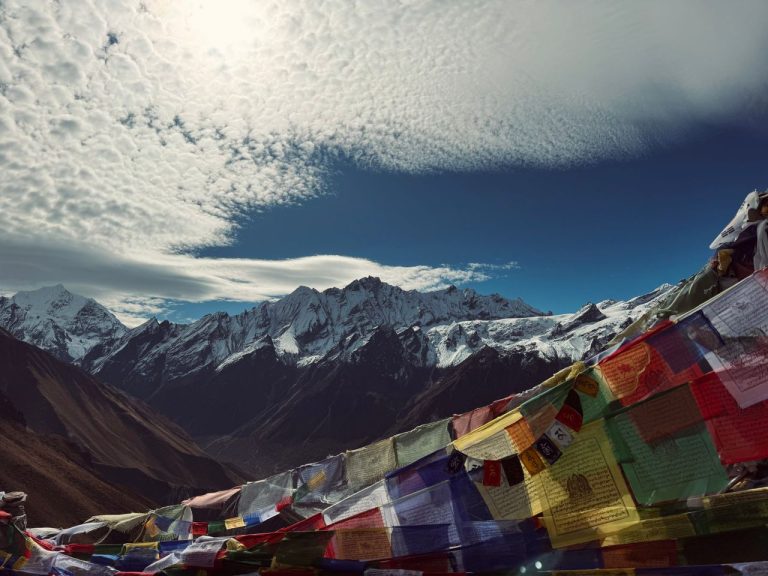 Scenic view of snow-capped Himalayas with vibrant Tibetan prayer flags fluttering, creating a peaceful atmosphere.
