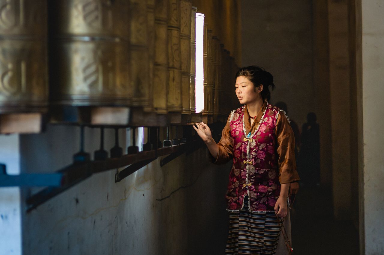 A Tibetan woman turns prayer wheels inside a temple in Sichuan, China.