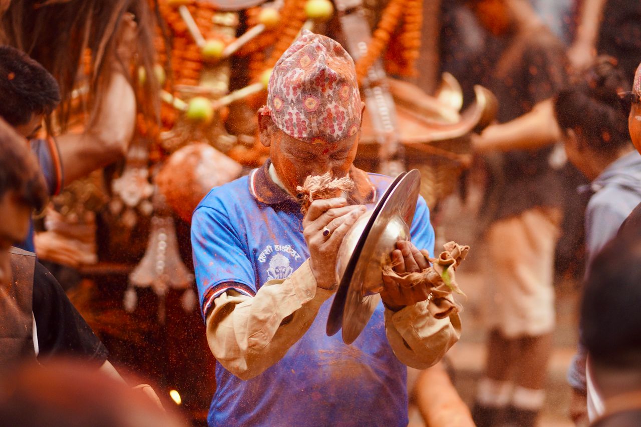 A lively Nepali New Year festival scene with a man playing a musical instrument amidst colorful festivities.